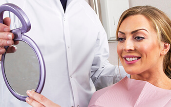 Woman and dentist examine smile in mirror