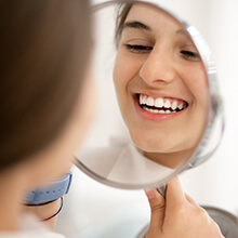 Girl examining perfect smile in mirror
