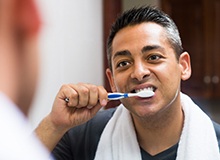 Young man with dental implants in Westfield brushing his teeth