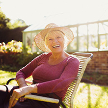 Senior woman with straw hat sitting outside and smiling