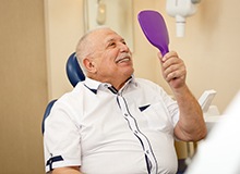 Senior man checking smile in mirror