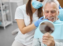 a patient checking his new teeth with a mirror