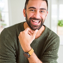 Man in green shirt smiling at home after root canal