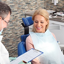 Dentist and patient smiling while reviewing cost of treatment