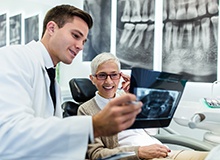 Dentist reviewing X-ray with smiling patient