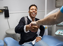Patient smiling while shaking dentist's hand