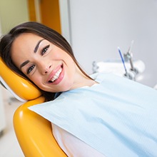Woman laying back in dental chair and smiling