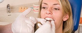 Dentist placing woman's Invialign alignment tray