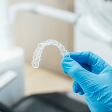 Gloved hand holding a clear aligner