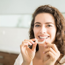 Woman with curly hair about to put in Spark clear aligner