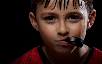 Young boy holding sportsguard in mouth
