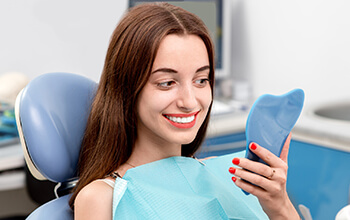 Woman examines smile in mirror