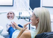 Patient using mirror to admire results of her cosmetic dentistry treatment
