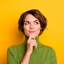Attractive woman in green turtleneck with questions about veneers