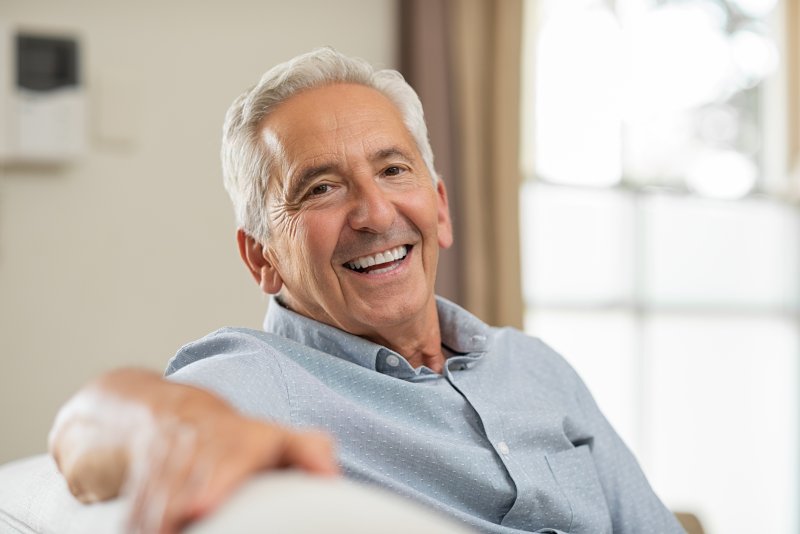 an older man sitting on a couch and smiling