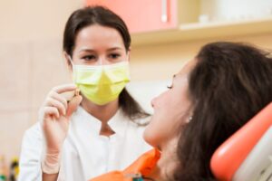 Dental team member showing patient her extracted tooth 